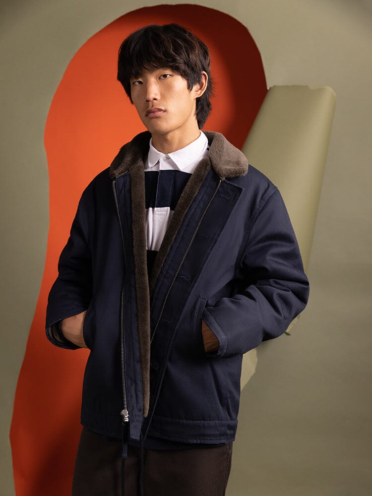 A person wearing the 1940s N-1 Deck Jacket in navy blue by Alpha Industries, featuring a fur collar.