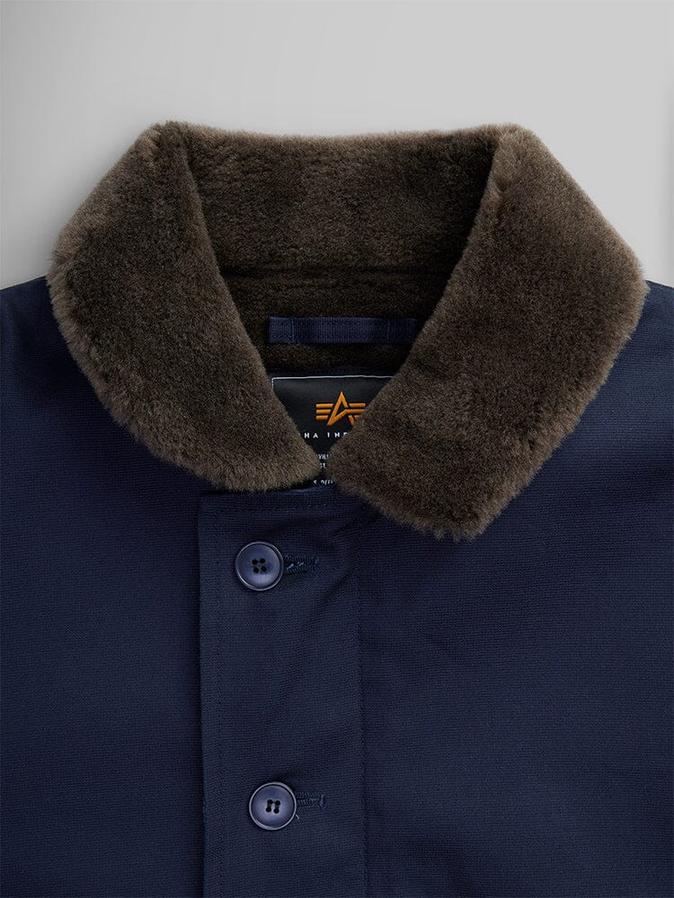 Close-up of the 1940s N-1 Deck Jacket by Alpha Industries. A navy blue jacket with a cotton shell and dark brown faux fur collar, inspired by classic US Navy deck jackets and featuring a button closure.