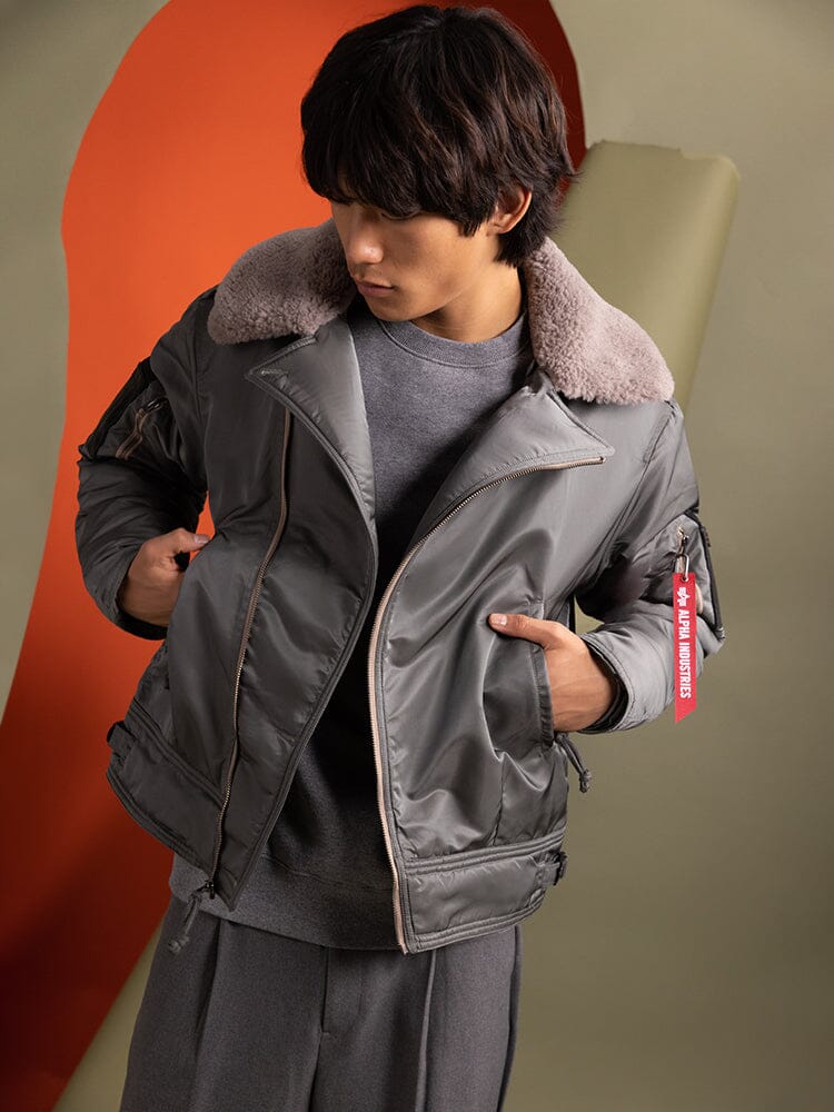 A person wearing the 1960s RCAF Canadian Airforce Type III Jacket by Alpha Industries, a stylish gray, water-resistant piece featuring a fur collar and utility pockets.