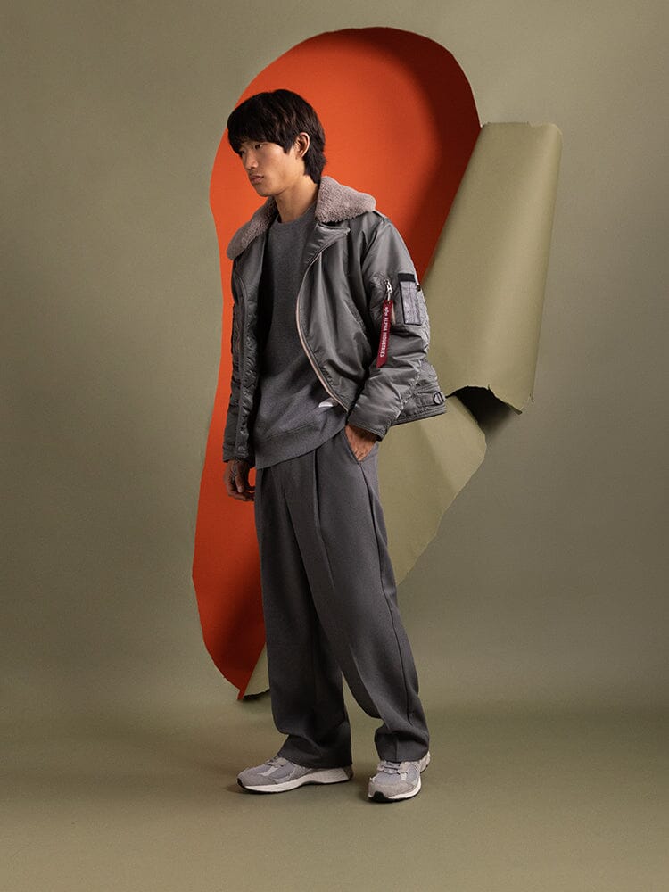 A person wearing the water-resistant 1960s RCAF Canadian Airforce Type III Jacket in field gray from Alpha Industries.