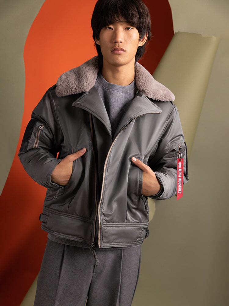 A person wearing the 1960s RCAF Canadian Airforce Type III Jacket by Alpha Industries, featuring a water-resistant fabric with a fur collar and utility pockets.