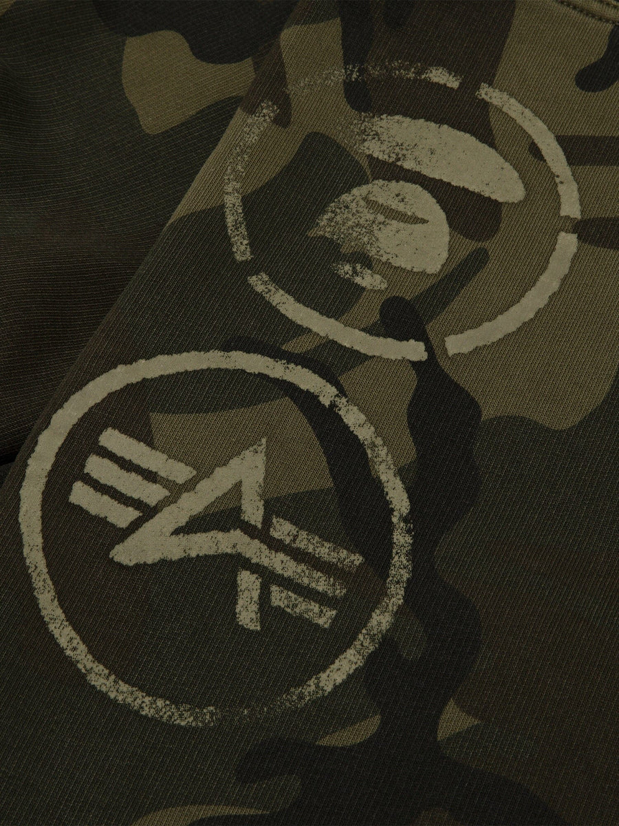 Aape X Alpha Camo Army Sweatpant by Alpha Industries, green camouflage fabric with two light-toned circular stenciled symbols.