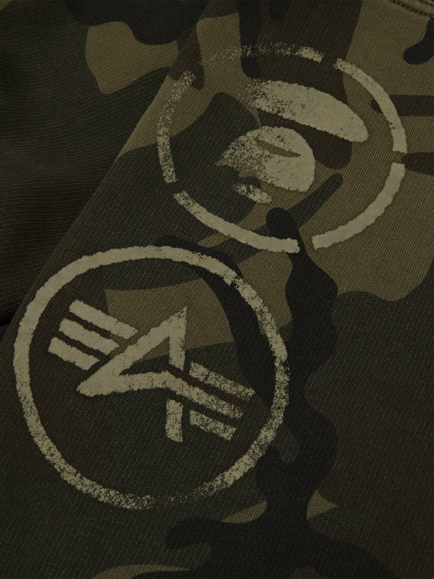 Aape X Alpha Camo Army Sweatpant by Alpha Industries, green camouflage fabric with two light-toned circular stenciled symbols.