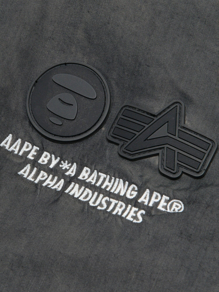 Aape X Alpha Reversible Padded MA-1 Quilted Jacket by Alpha Industries, black logo patches, white embroidery, quilted design.