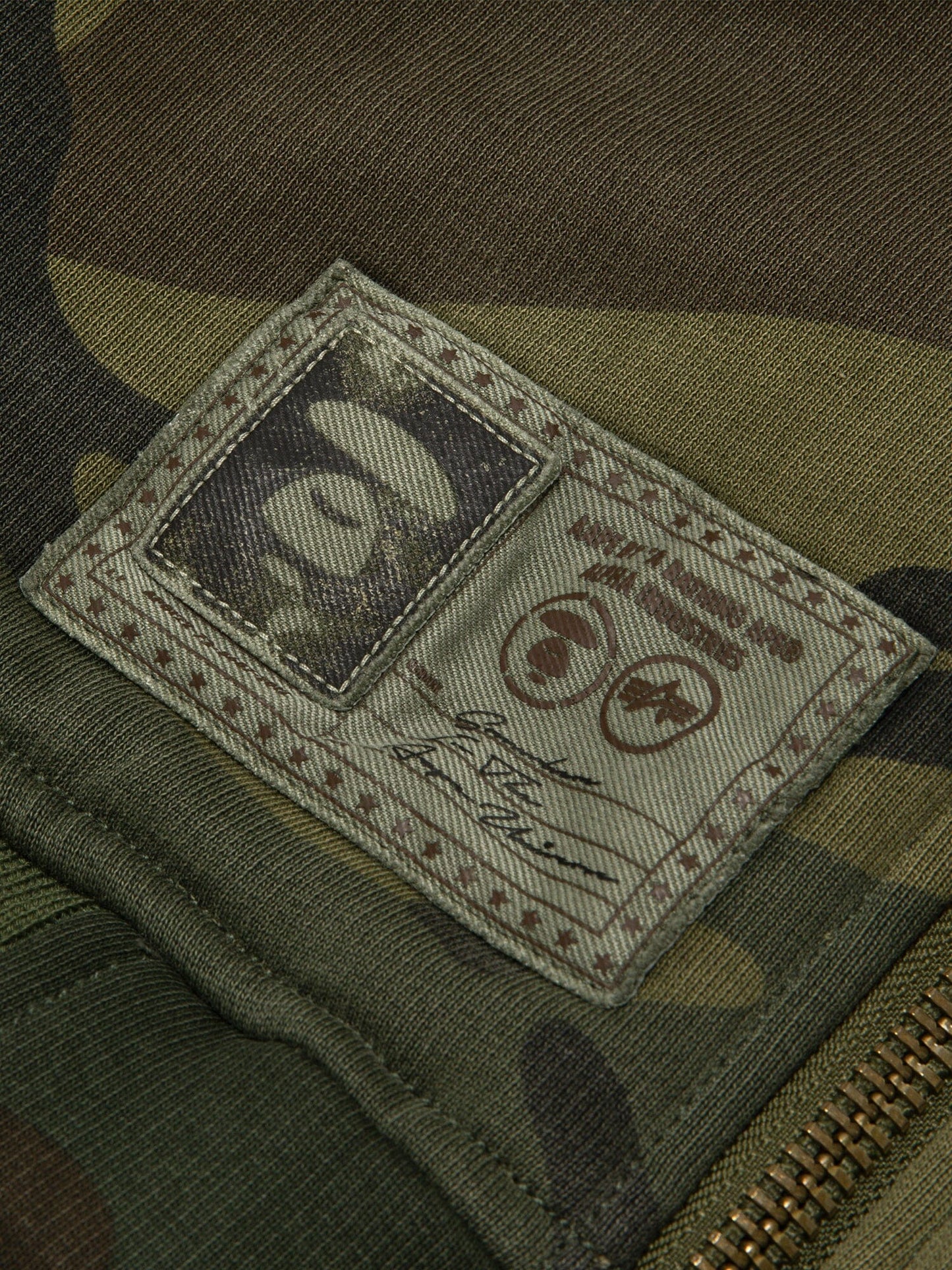 Aape X Alpha Reversible Padded MA-1 Quilted Jacket by Alpha Industries, camouflage, stitched logo patch, signature detail, visible zipper.