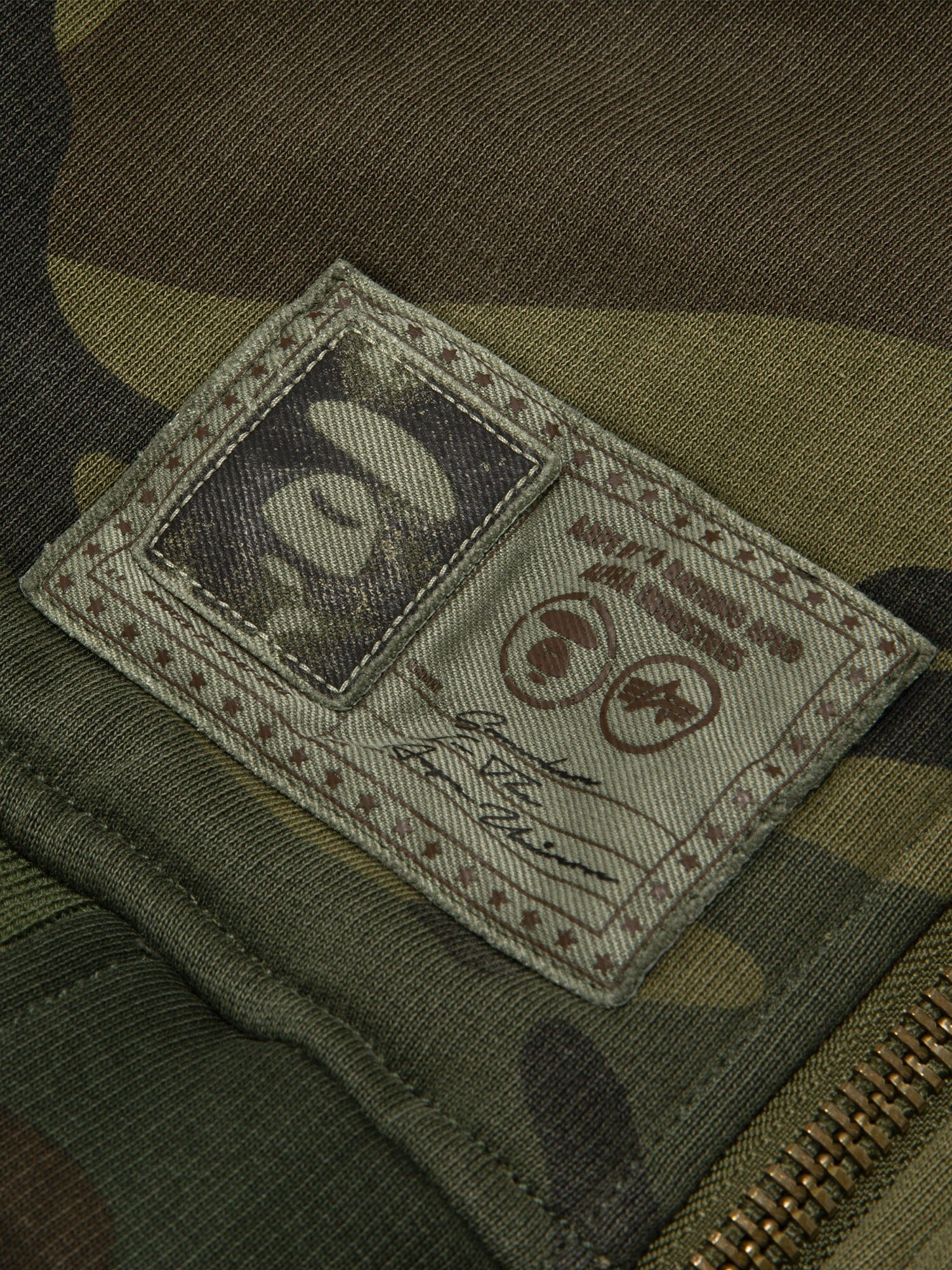 Aape X Alpha Reversible Padded MA-1 Quilted Jacket by Alpha Industries, camouflage, stitched logo patch, signature detail, visible zipper.