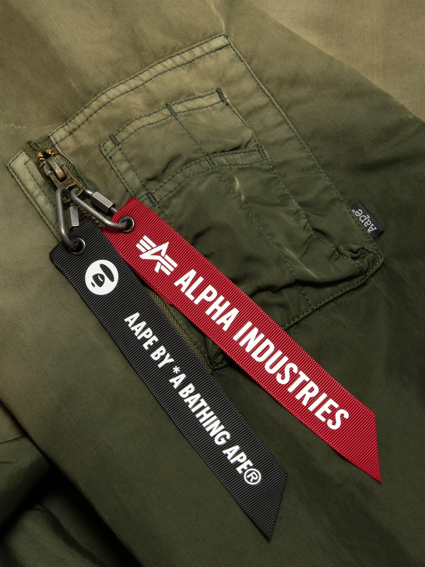 Aape X Alpha Reversible Padded MA-1 Quilted Jacket by Alpha Industries, green pocket with two keychains: red Alpha Industries and black Aape By *A Bathing Ape.