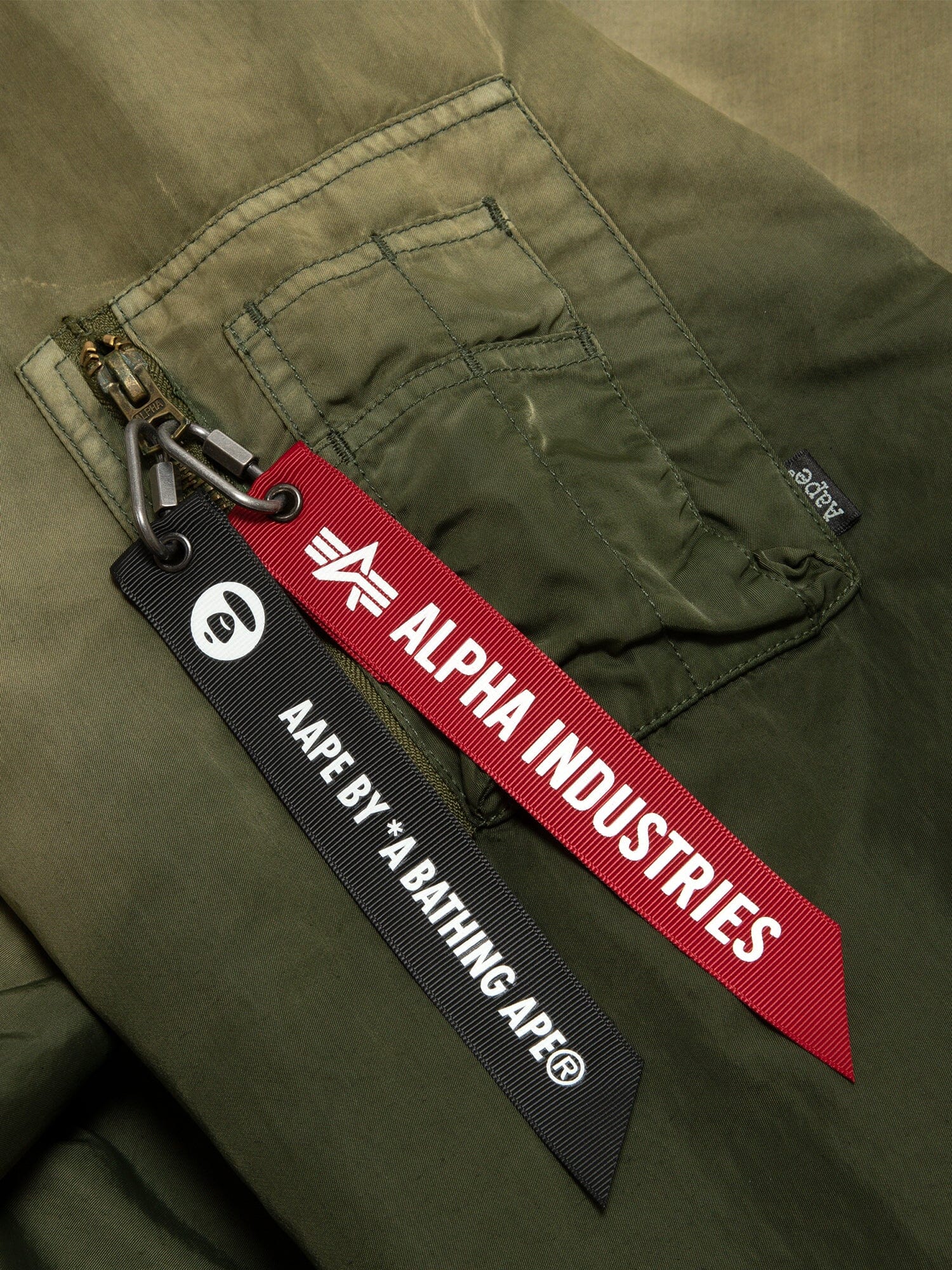 Aape X Alpha Reversible Padded MA-1 Quilted Jacket by Alpha Industries, green pocket with two keychains: red Alpha Industries and black Aape By *A Bathing Ape.