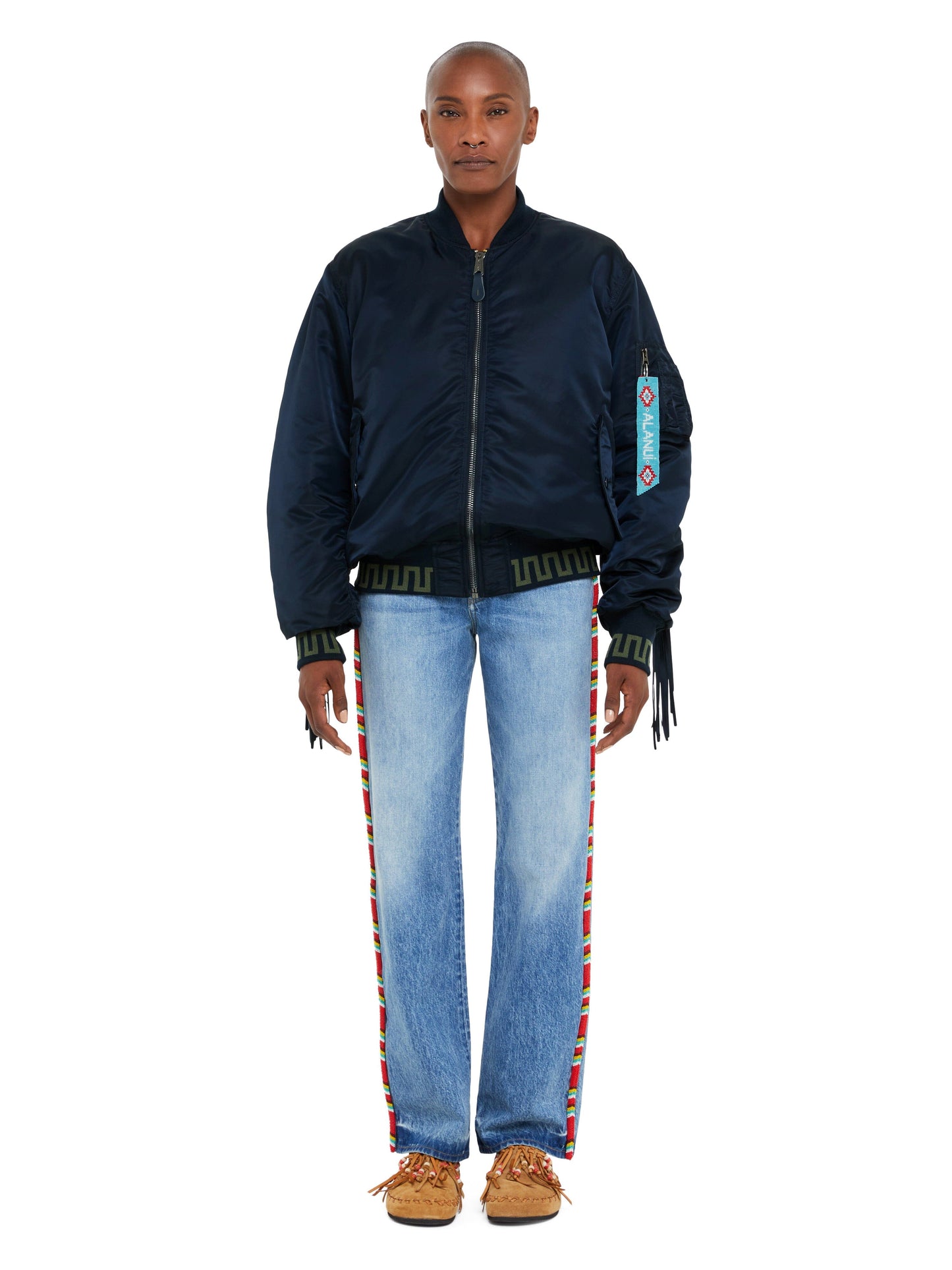 ALANUI X Alpha Industries MA-1 Jacket, light blue jeans with colorful side stripes, brown moccasins.