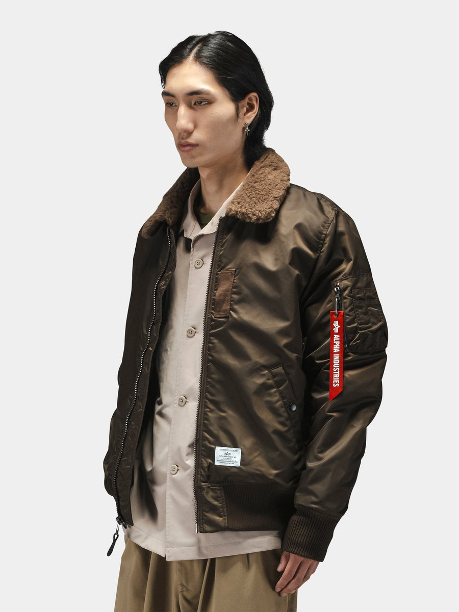 Alpha Industries B-15 Mod Bomber Jacket with faux mouton collar, beige shirt, and tan pants.