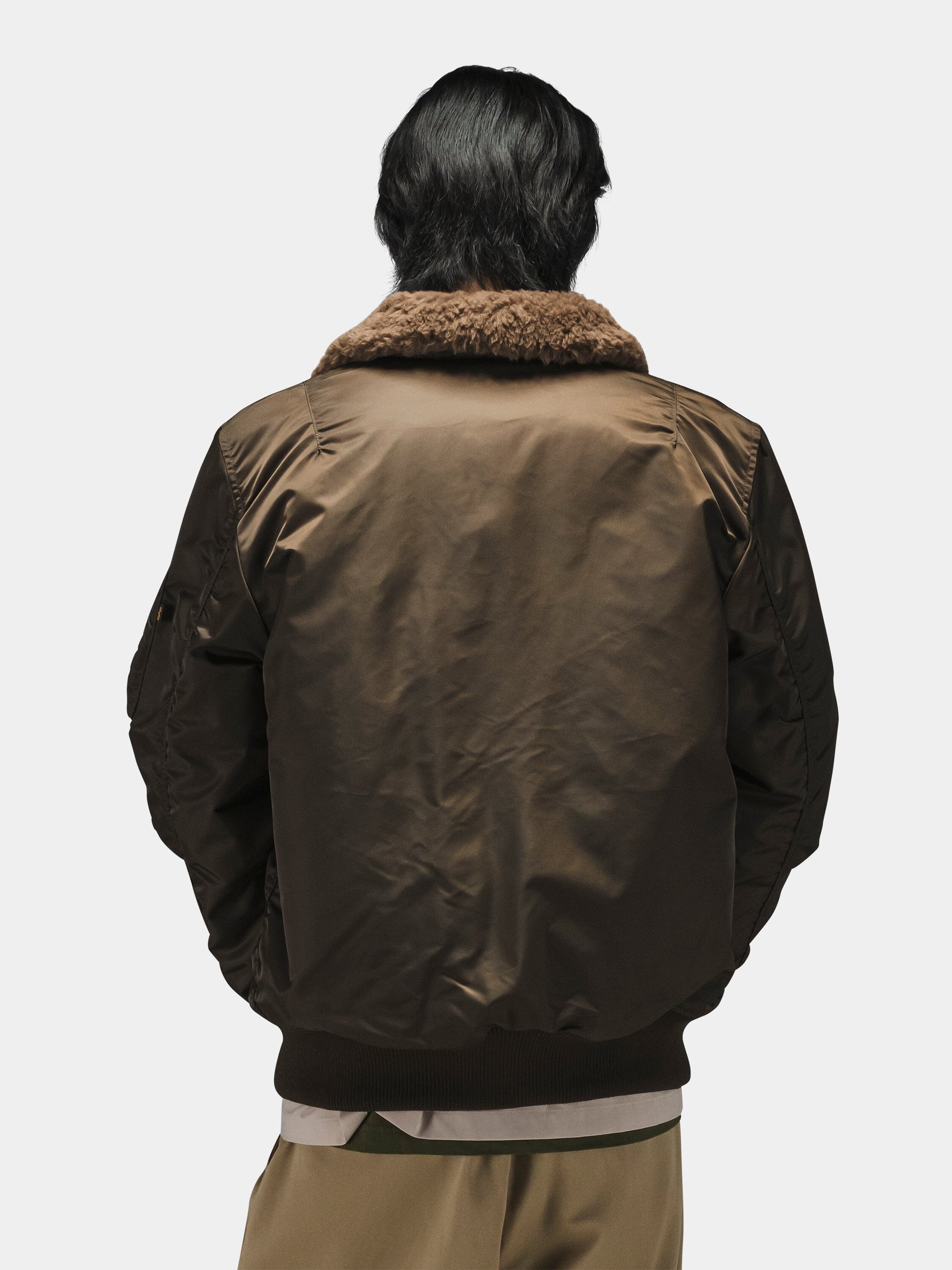 Alpha Industries B-15 Mod Bomber Jacket in brown with faux mouton collar, paired with khaki pants.