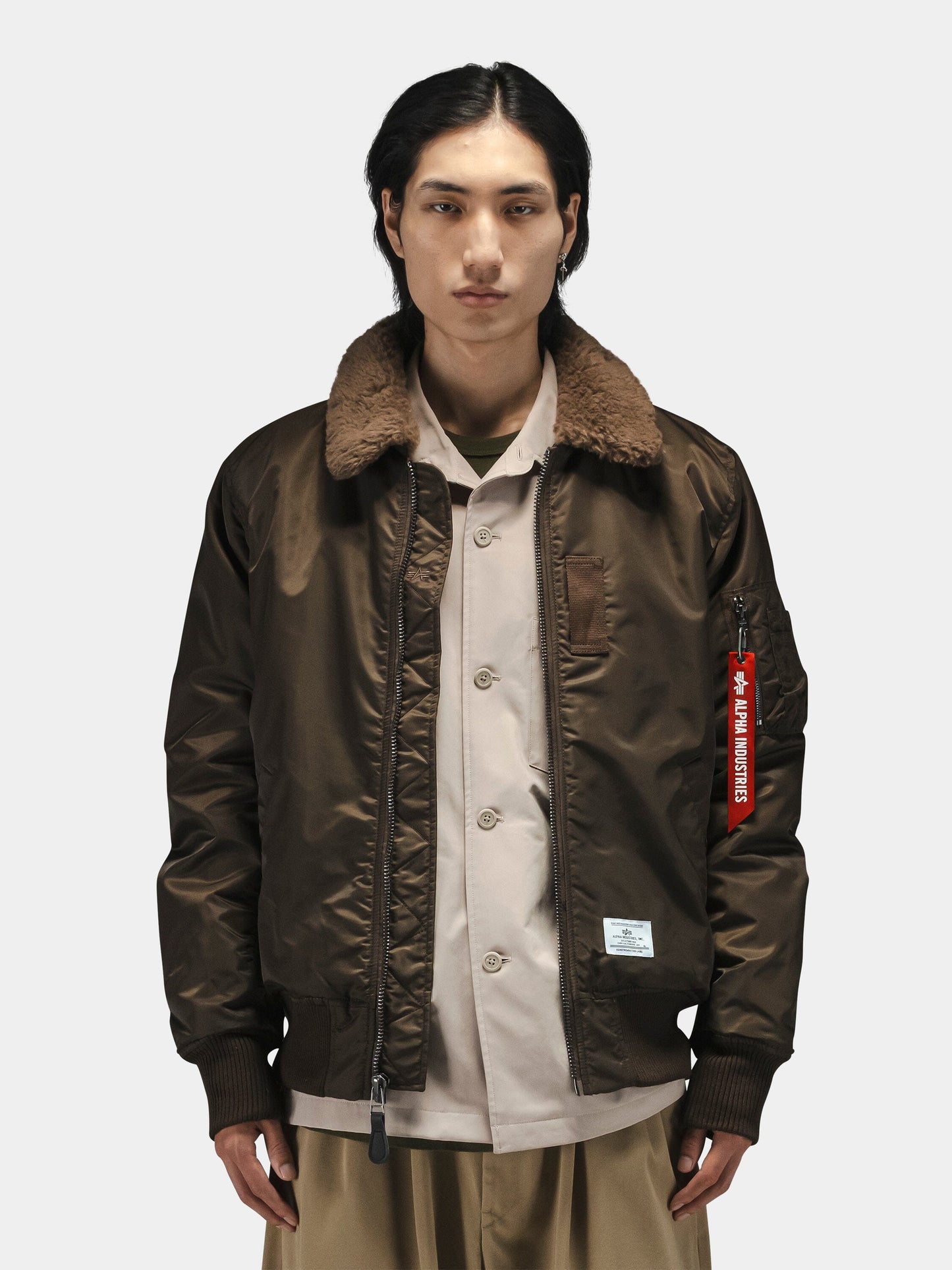 B-15 Mod Bomber Jacket by Alpha Industries with brown faux mouton collar, beige shirt, and tan pants.