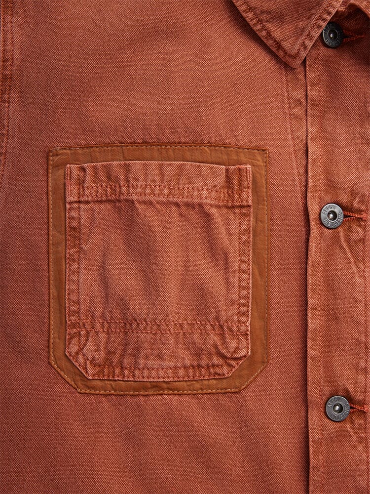 Alpha Industries Ctn Chore Coat, rust color, garment-washed cotton, button-up closure, chest pocket with darker trim, visible stitching.