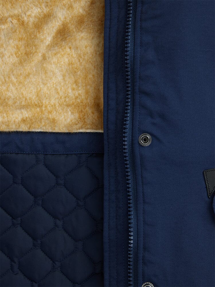Close-up of the Elyse Gen II Parka W in navy blue by Alpha Industries, highlighting a quilted pattern, faux fur lining, and a vertical zipper with metal snap buttons.