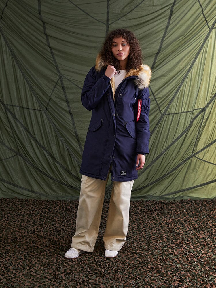 A person wearing the Elyse Gen II Parka W in navy blue from Alpha Industries.