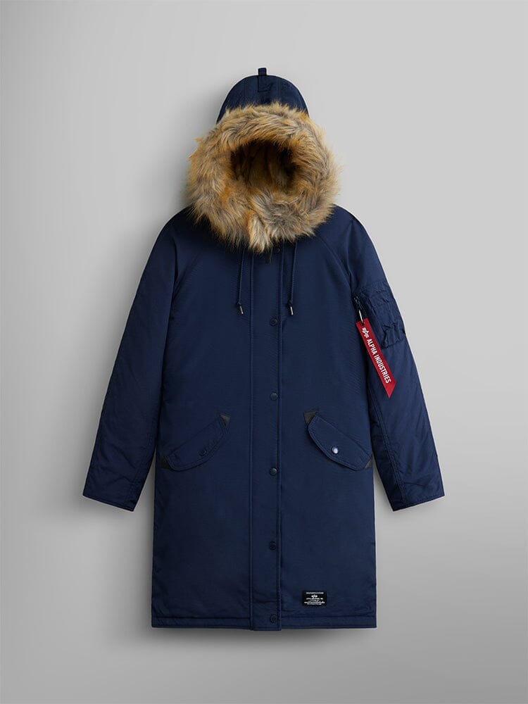 The Elyse Gen II Parka W from Alpha Industries, in replica blue, features a water-resistant finish with a faux fur-lined hood and a distinctive red tag on the sleeve.