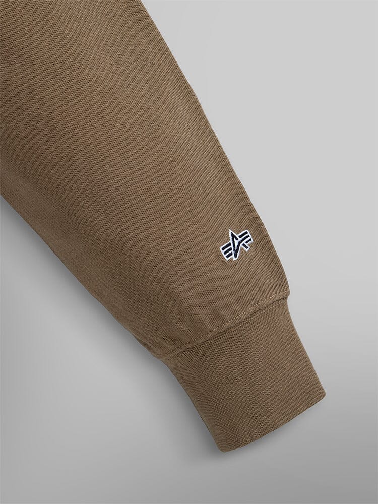 Close-Up of the Brown Sleeve from the Essential Crewneck by Alpha Industries, Featuring a Small Logo Near the Cuff.