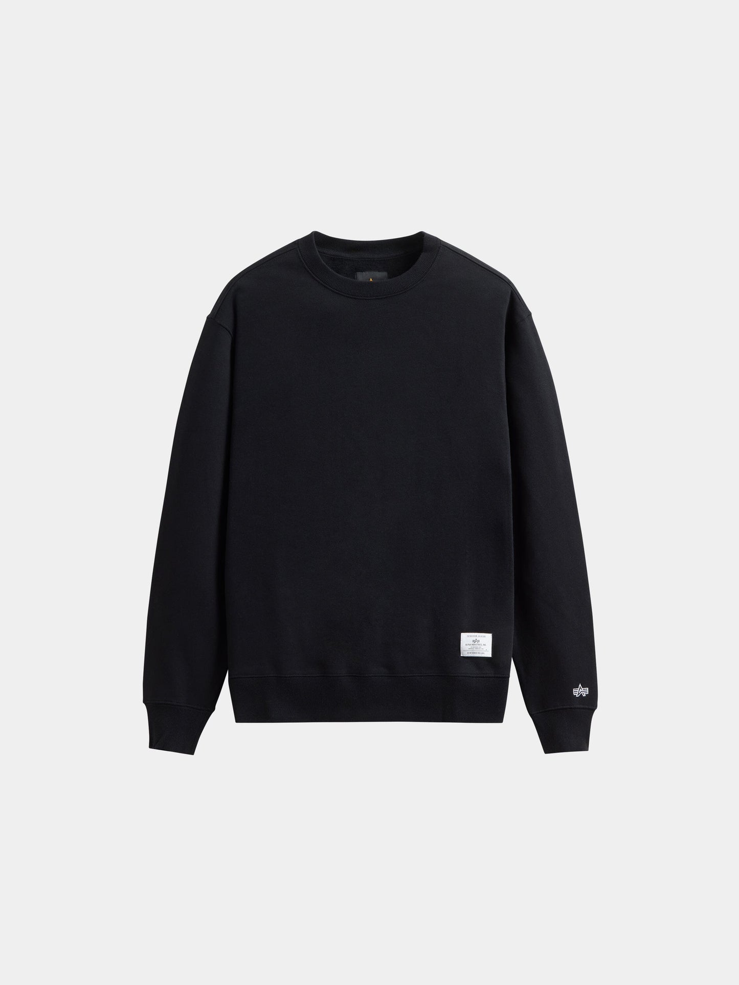 Alpha Industries Essential Crewneck, black sweater with long sleeves, ribbed cuffs and hem, and a small white tag near the waistband.
