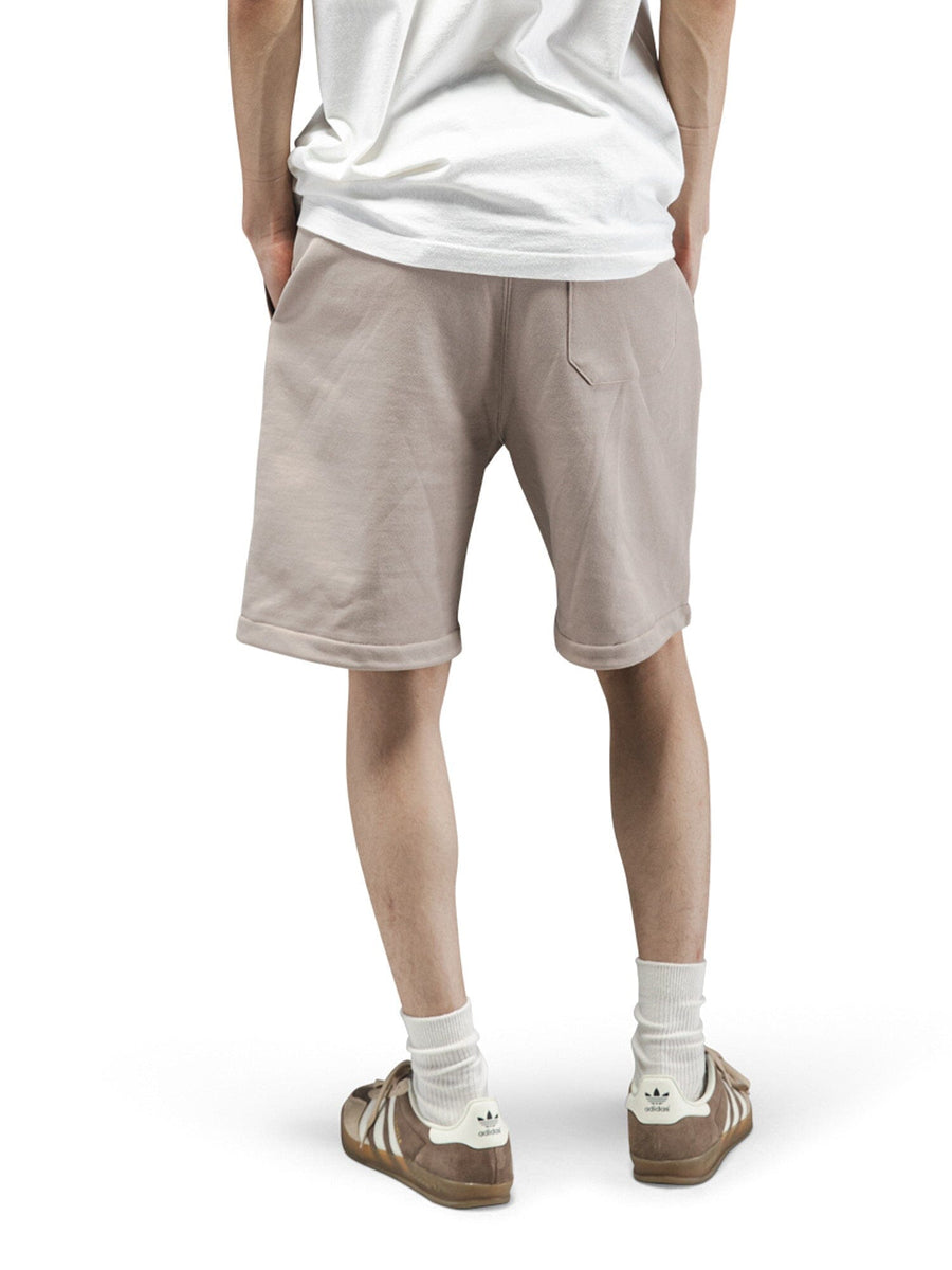 Alpha Industries Essential French Terry Short in beige with white T-shirt, white socks, and brown Adidas sneakers.