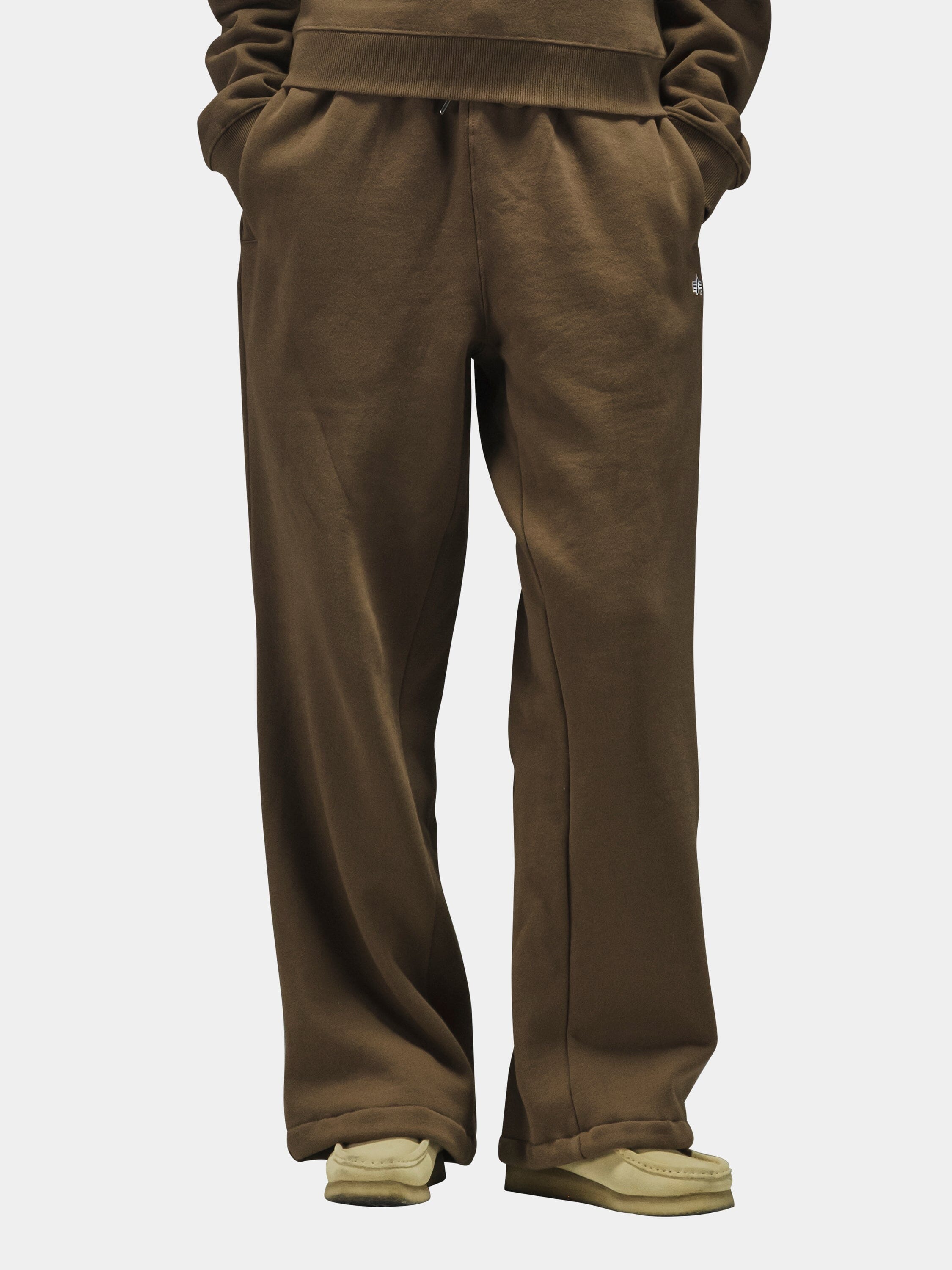 Alpha Industries Essential Sweatpants in beige with elastic waistband and cuffs, paired with beige shoes.