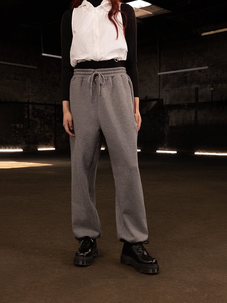 Alpha Industries Essential Sweatpants in grey with elastic waistband and cuffs; white sleeveless vest, black top, black platform shoes.