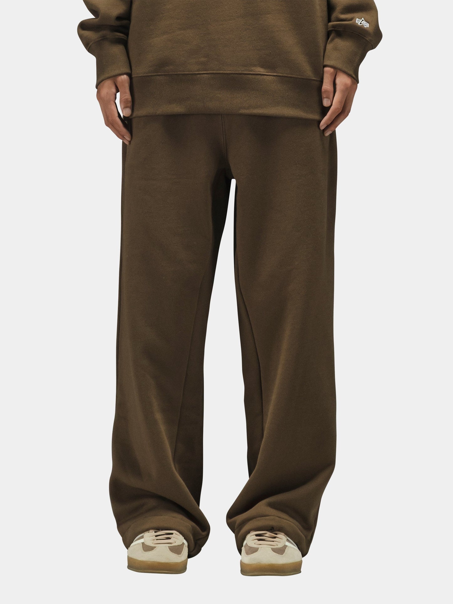 Alpha Industries Essential Sweatpants in black, paired with beige sneakers.