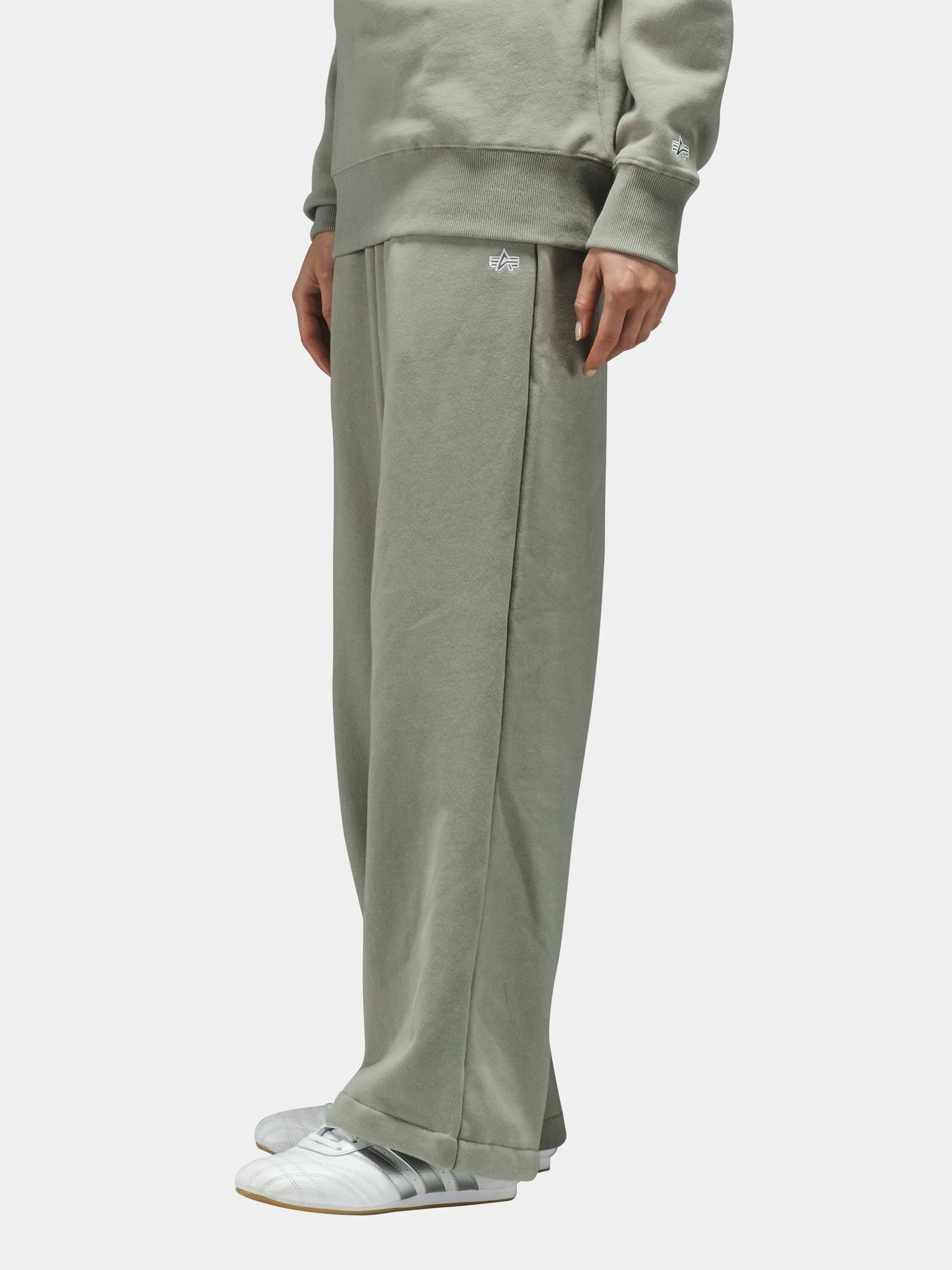 Essential Sweatpants and matching sweatshirt by Alpha Industries in sage green with white Adidas sneakers.