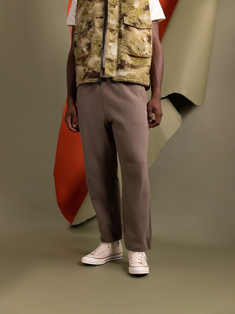 Essential Sweatpants Coyote Brown by Alpha Industries, camouflage vest, white tee, white sneakers.