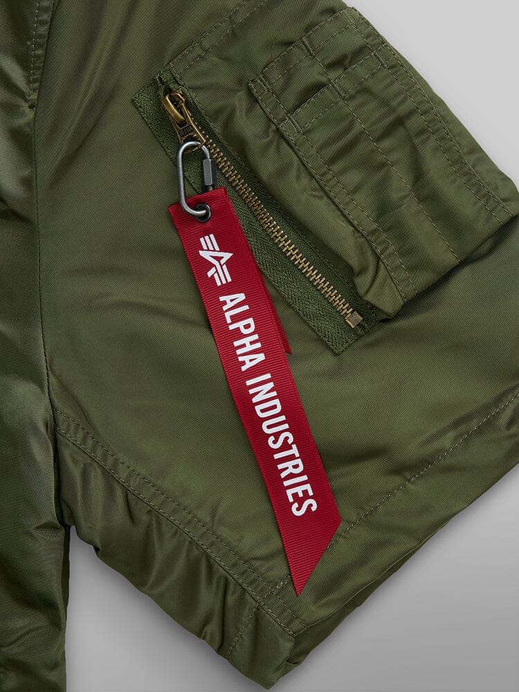 L-2B Short Sleeve Bomber Jacket by Alpha Industries, green nylon with utility pocket and red branded tag on zipper pull.