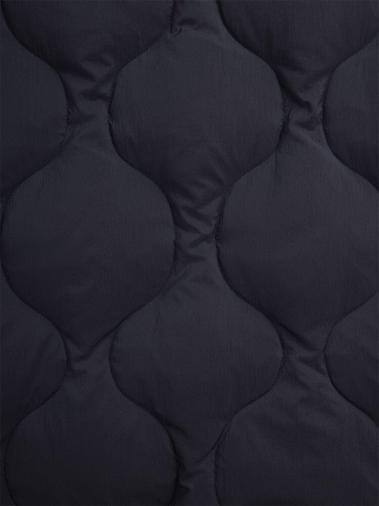 Close-up of the fabric from the Lightweight Quilted Down Jacket in black by Alpha Industries, featuring a rounded quilted pattern that offers a textured appearance.