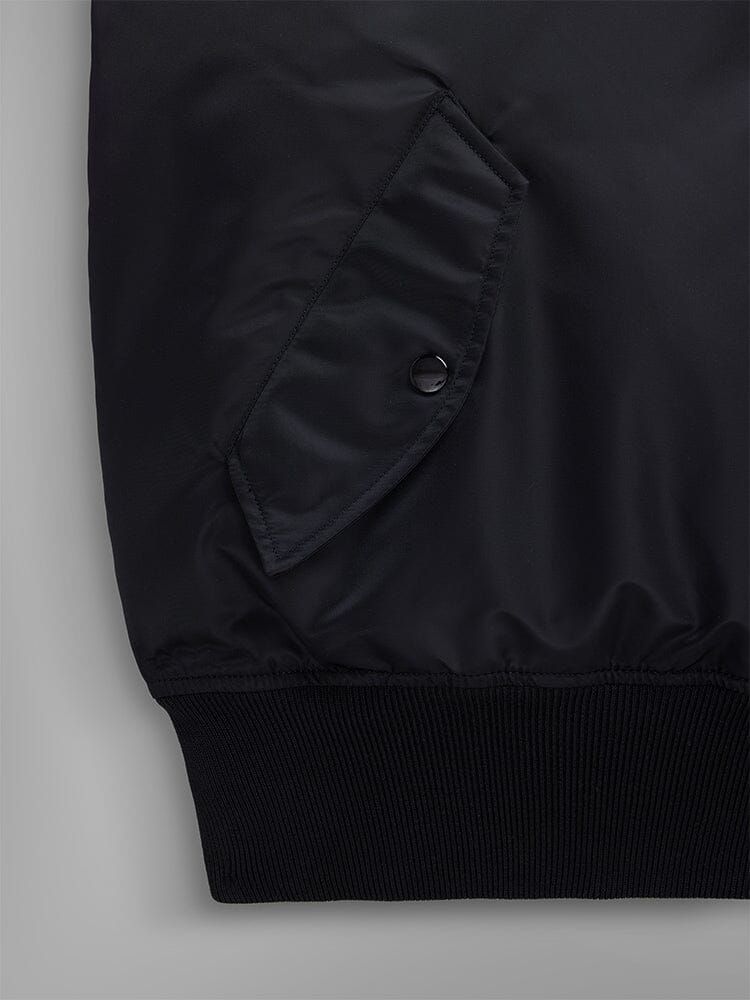 Close-up pocket view of the Pull-Over MA-1 Jacket Hoodie by Alpha Industries, showcasing its iconic black flight nylon design with a snap-button utility pocket and ribbed hem.