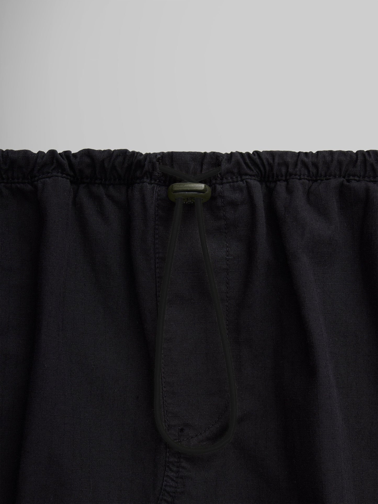 Close-up of the Women's Drawcord Skirt by Alpha Industries, showcasing its black fabric with a bungee waistband and drawstring tied in a loop.