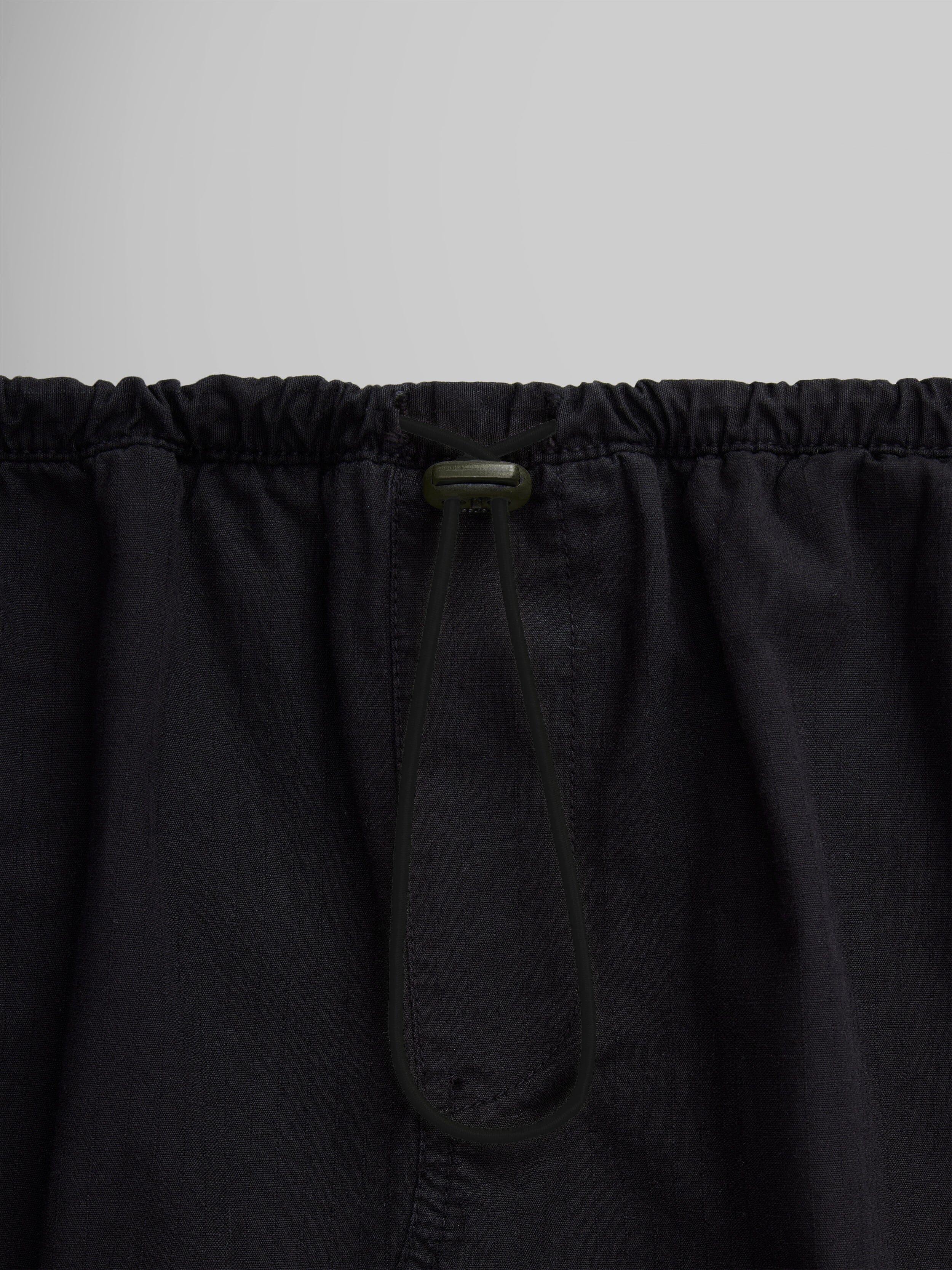 Close-up of the Women's Drawcord Skirt by Alpha Industries, showcasing its black fabric with a bungee waistband and drawstring tied in a loop.