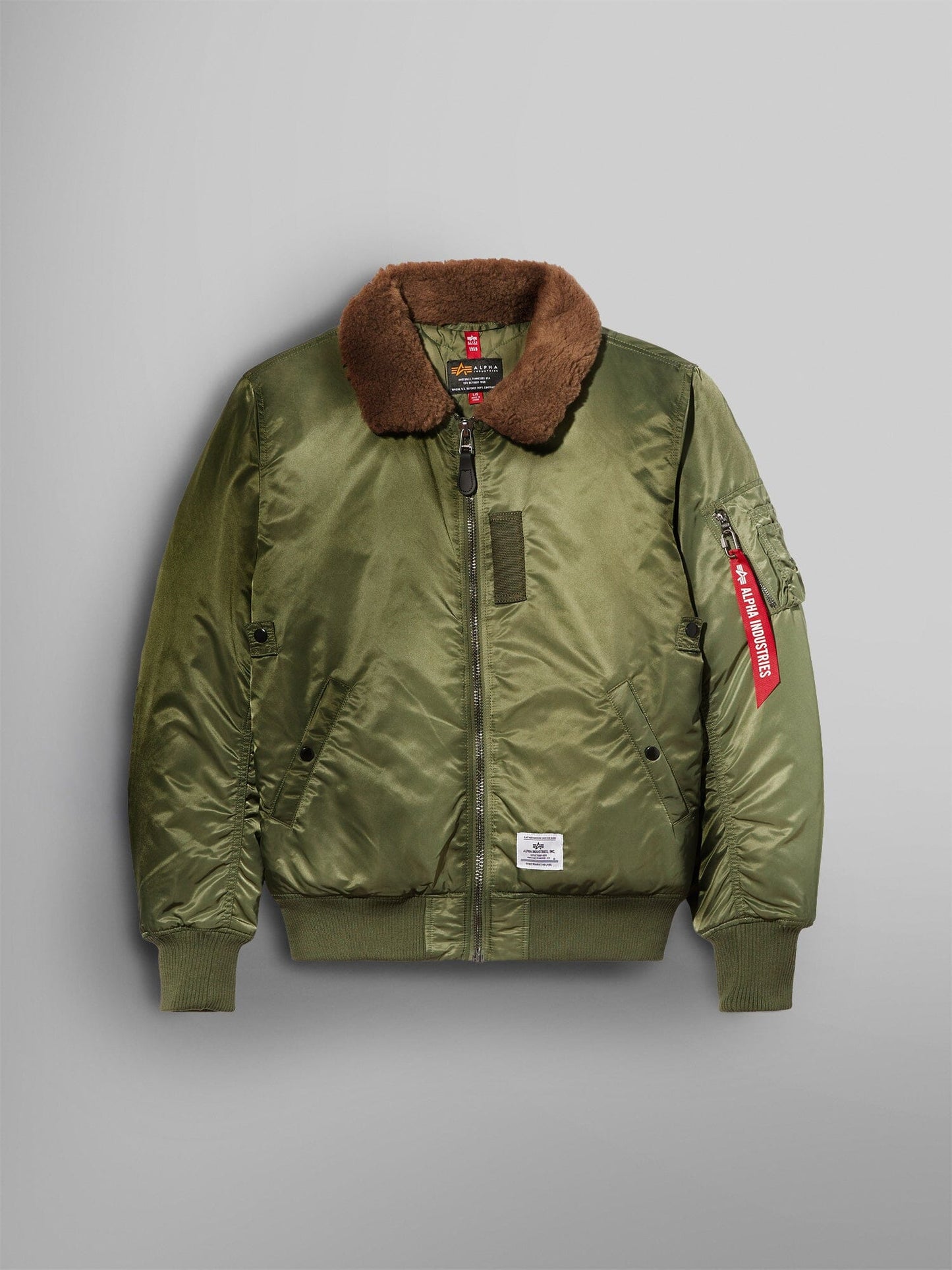 Alpha Industries B-15 Mod Bomber Jacket in sage with brown faux mouton collar, front zipper, ribbed cuffs and hem, red sleeve tag.