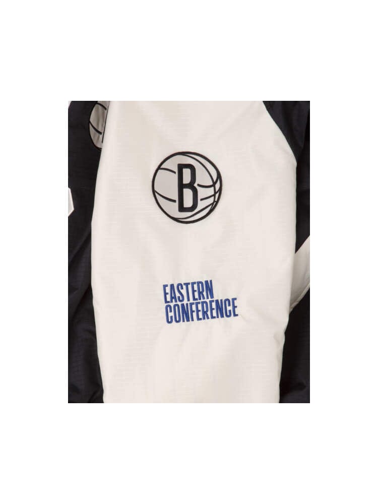 A close-up of the Brooklyn Nets x Alpha x New Era L-2B Bomber Jacket, featuring a basketball logo with the letter B and "Eastern Conference" text in blue, complemented by team patches. The pinstripe interior enhances this Alpha Industries must-have piece with a touch of classic style.