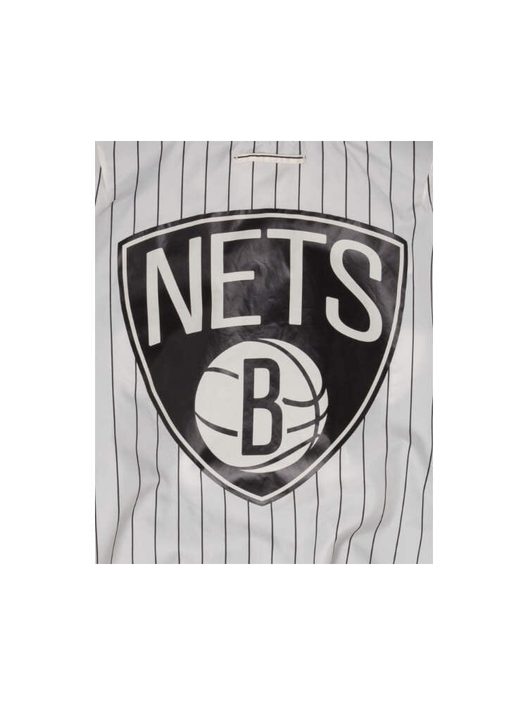 This jacket, branded as the Brooklyn Nets x Alpha Industries x New Era L-2B Bomber Jacket, boasts a vertical striped design with a bold Brooklyn Nets logo and team patches on the interior pinstripe lining.