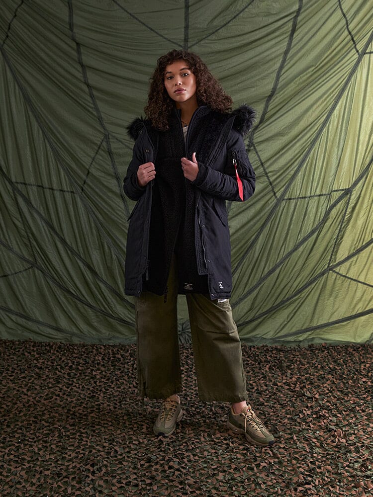 A person wearing the Elyse Gen II Parka W in black from Alpha Industries.