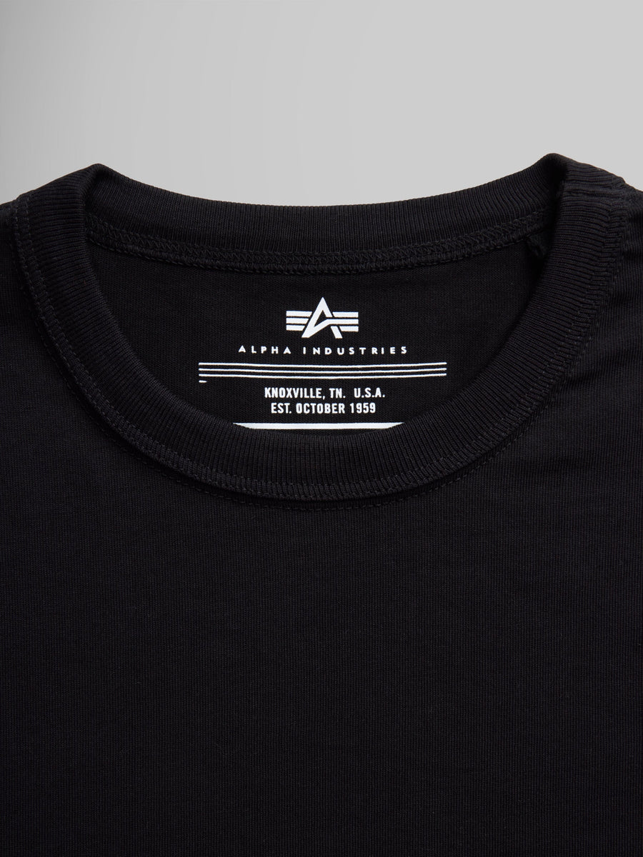 Black Alpha Industries Essential Tee collar and label with brand logo and establishment details.