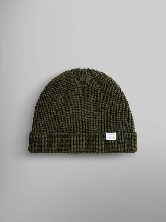 A wool-blend watch cap in olive color featuring a folded brim and a small white label on the front, by Alpha Industries, named the Essential Watch Cap.