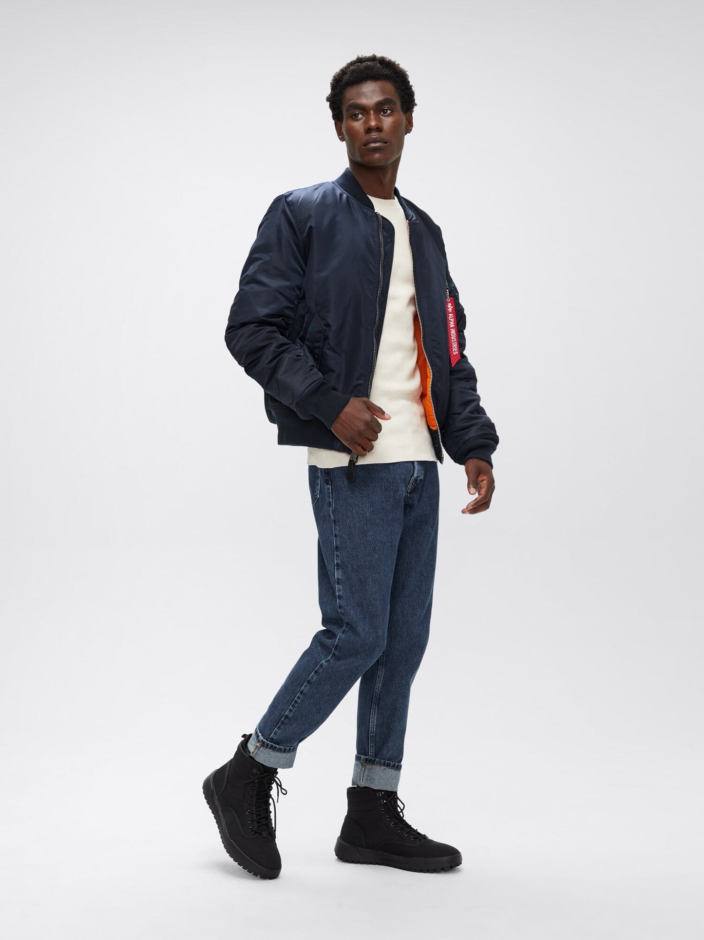 Full-body angled view of replica blue Alpha Industries MA-1 Bomber Jacket Slim Fit showing orange lining and ribbed cuffs.