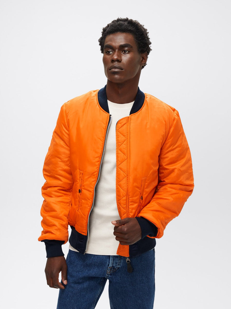 Three-quarter front view of orange reversible Alpha Industries MA-1 Bomber Jacket Slim Fit showing ribbed cuffs and waistband.