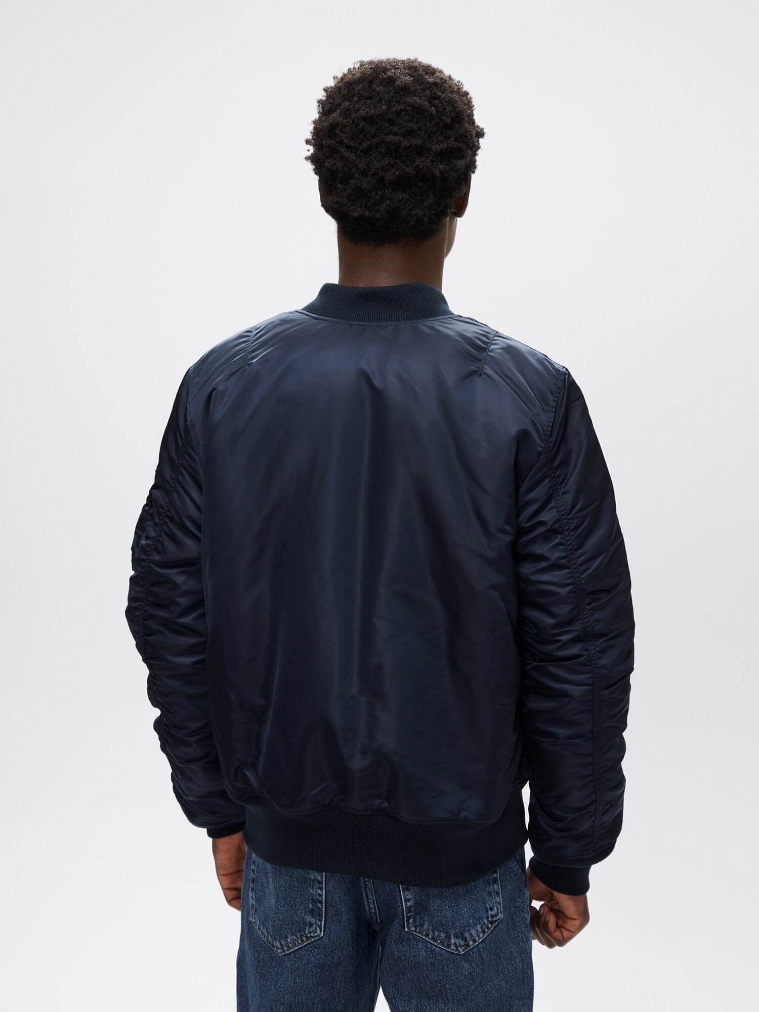 Back view of replica blue Alpha Industries MA-1 Bomber Jacket Slim Fit showing ribbed collar, cuffs, and waistband.