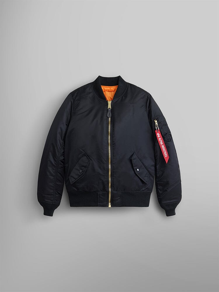 Alpha Industries MA-1 Bomber Jacket Womens in black with gold zipper, orange lining, and red Remove Before Flight tag on left sleeve.