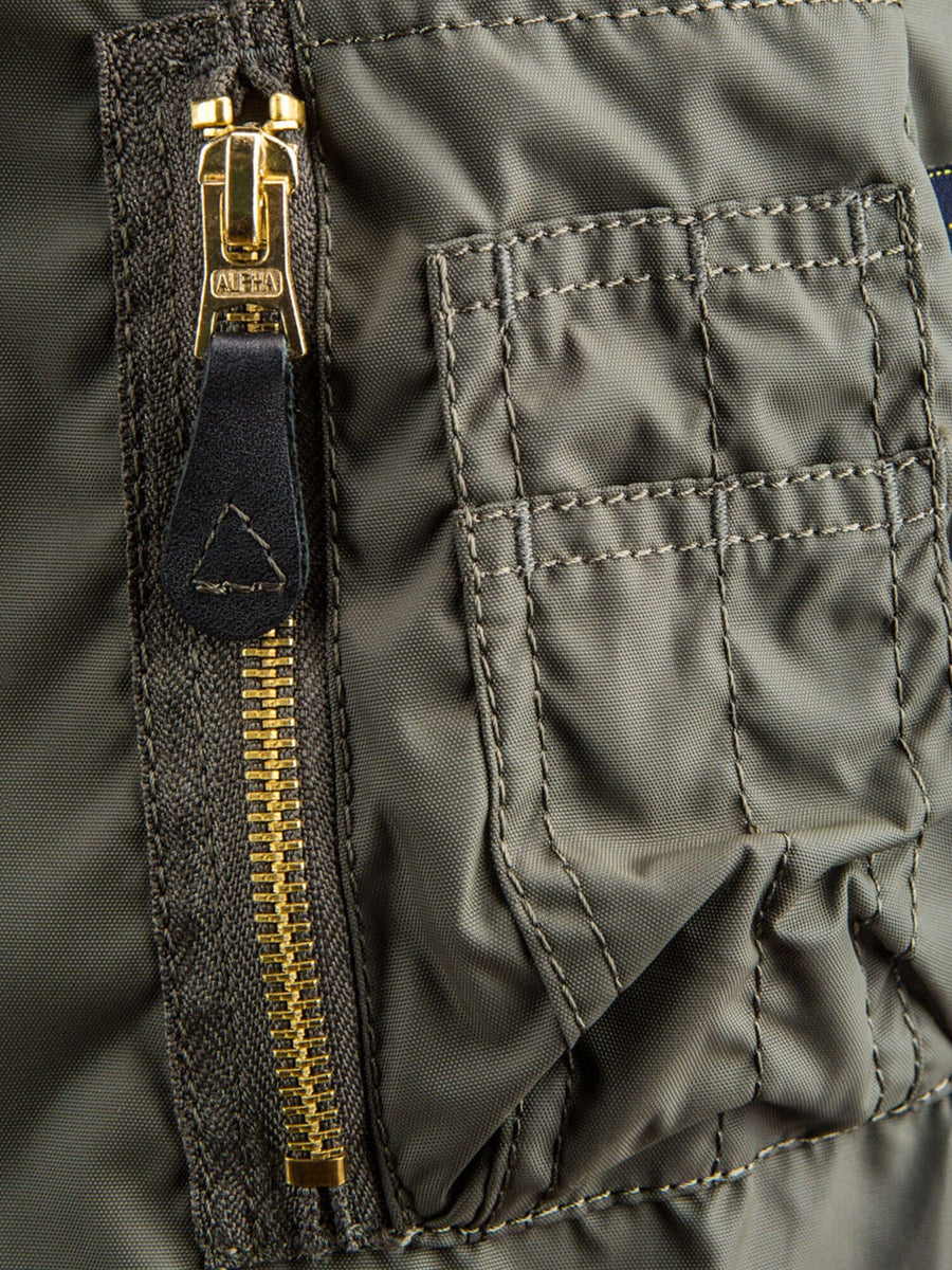 Alpha Industries MA-1 Skymaster Bomber Jacket in green, gold zipper, leather pull tab, stitched rectangular pocket with flap.