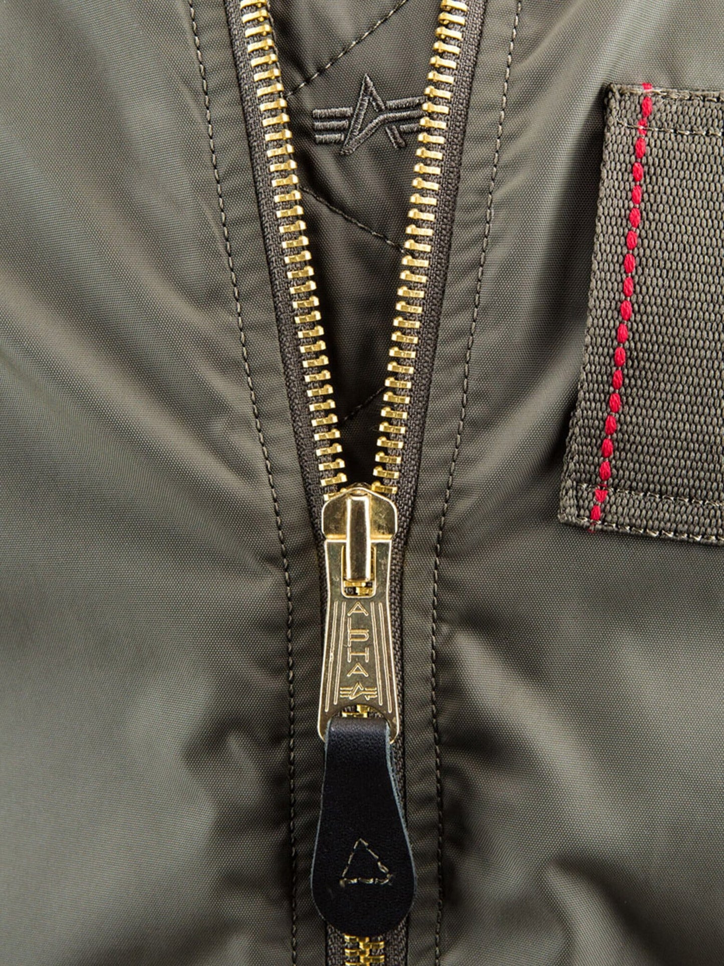 Alpha Industries MA-1 Skymaster Bomber Jacket, olive green, gold zipper, stitched patch in red thread, embroidered logo above the zipper.