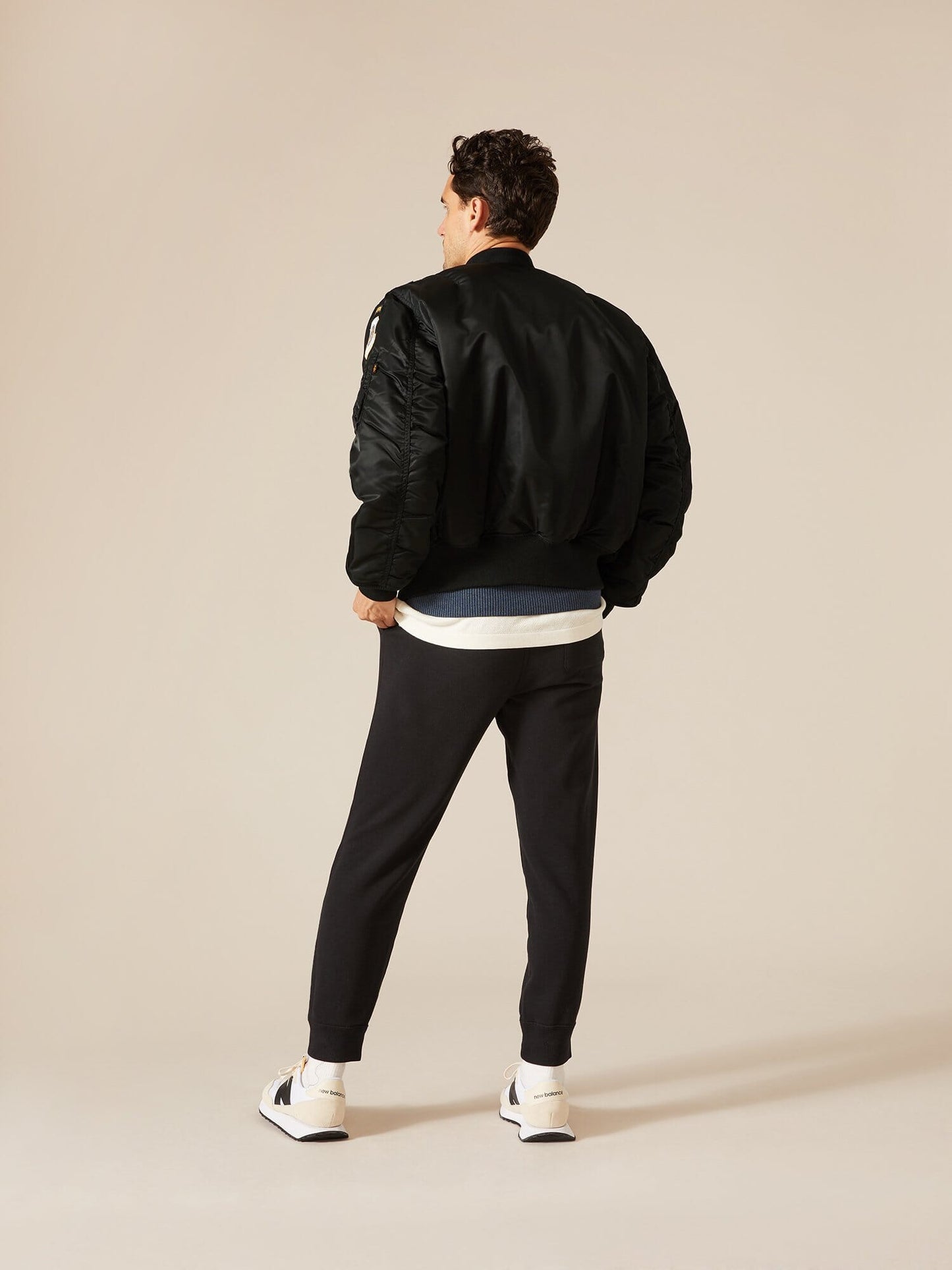 Alpha Industries MA-1 Squadron Bomber Jacket with squadron patches, dark jogger pants, white shirt, white sneakers.