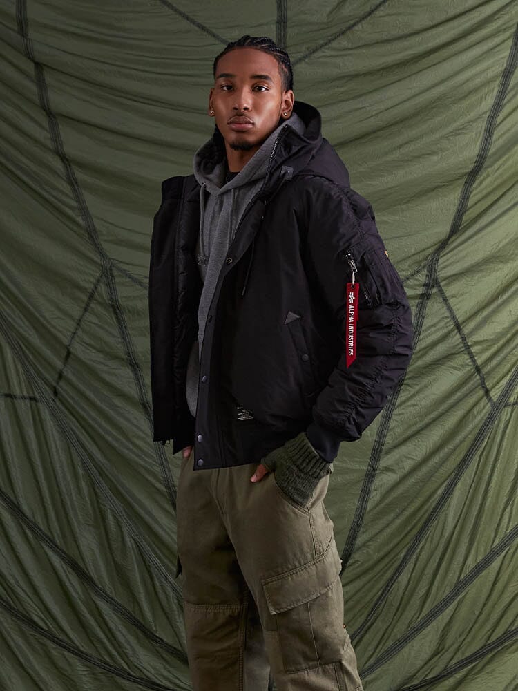 With confidence, the individual poses wearing the N-2B Altitude Parka in black from Alpha Industries.