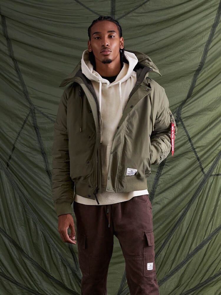 With confidence, the individual poses wearing the N-2B Altitude Parka in green from Alpha Industries.