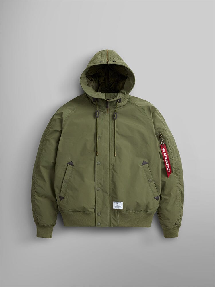 The N-2B Altitude Parka by Alpha Industries in OG-107 green is a bomber jacket with a water-resistant finish, featuring an adjustable split hood, a zipped sleeve pocket, and a red Alpha Industires tag.