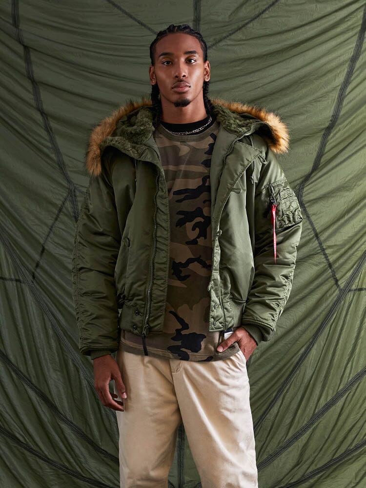 Alpha Industries N-2B Short Waist Parka with faux mouton fur trim, camouflage shirt, beige pants.